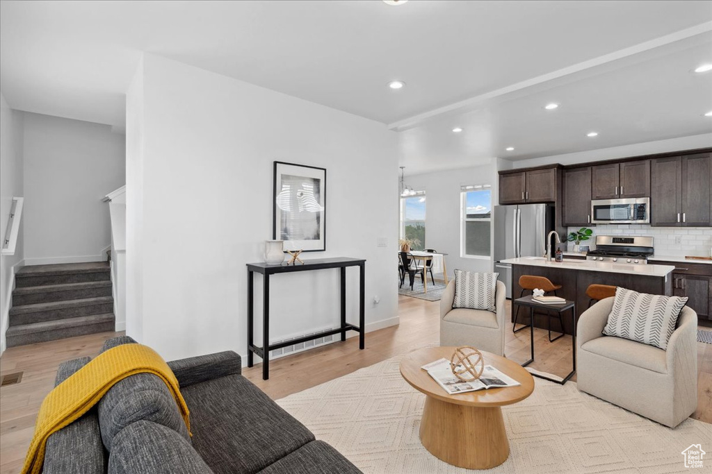 Living room featuring light wood-style flooring, recessed lighting, and stairway