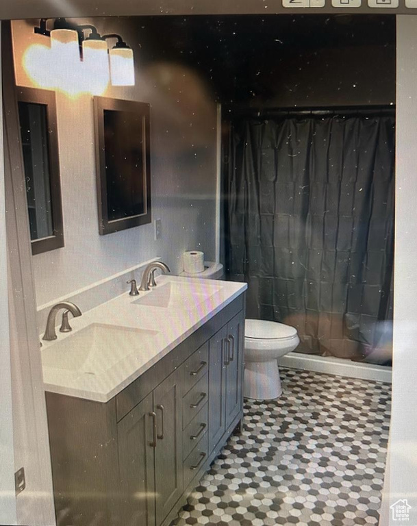 Full bath with double vanity, tile patterned floors, and a shower with shower curtain