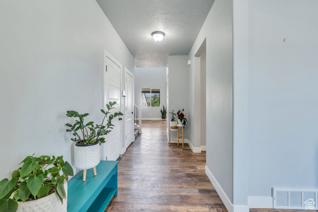 Hall with wood finished floors and a textured ceiling