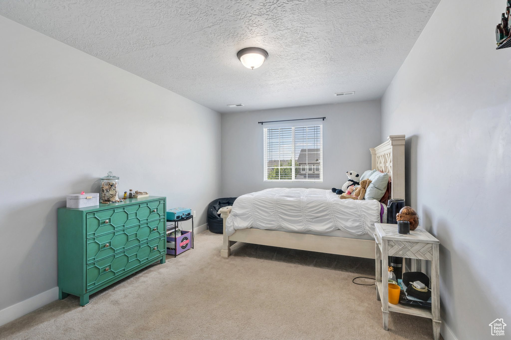 Bedroom with light colored carpet and a textured ceiling