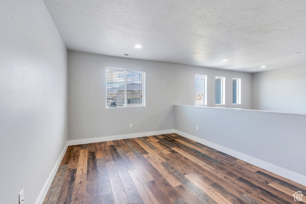 Empty room featuring a textured ceiling, wood-type flooring, and recessed lighting