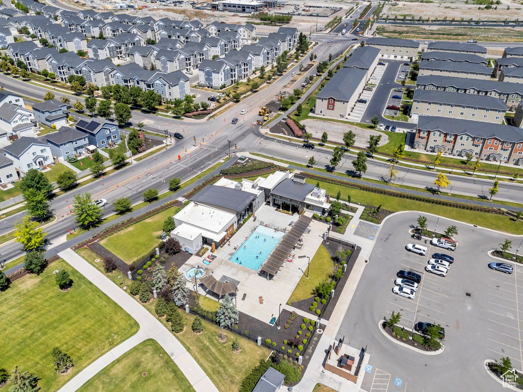 Aerial view of property and surrounding area featuring a pool and nearby suburban area
