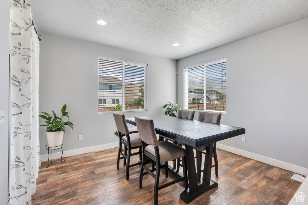 Dining area with wood finished floors, a textured ceiling, and recessed lighting