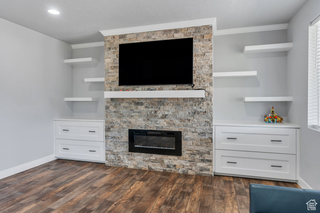 Detailed view of crown molding, wood finished floors, a stone fireplace, and recessed lighting
