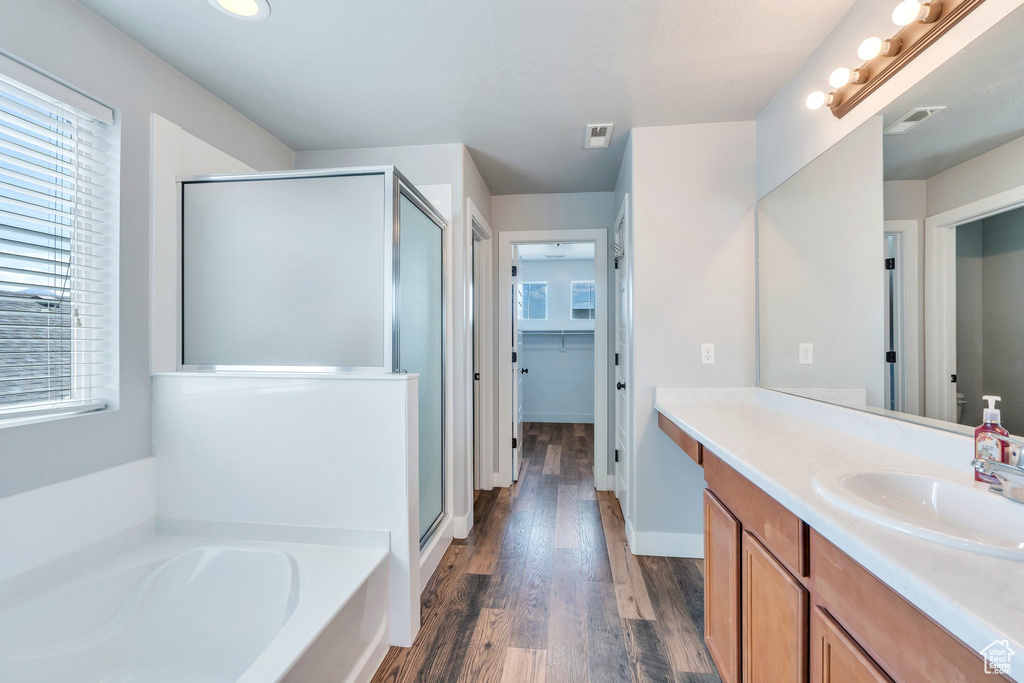 Bathroom featuring a stall shower, vanity, a bath, and wood finished floors