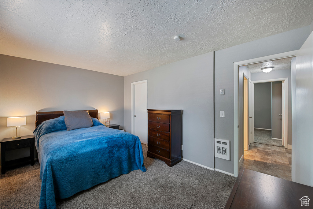 Bedroom with a textured ceiling, baseboards, and carpet
