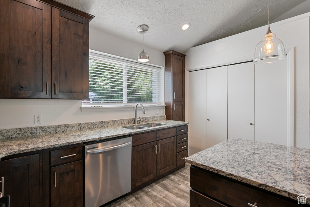 Kitchen featuring dishwasher, a sink, light wood-style floors, a textured ceiling, and dark brown cabinetry