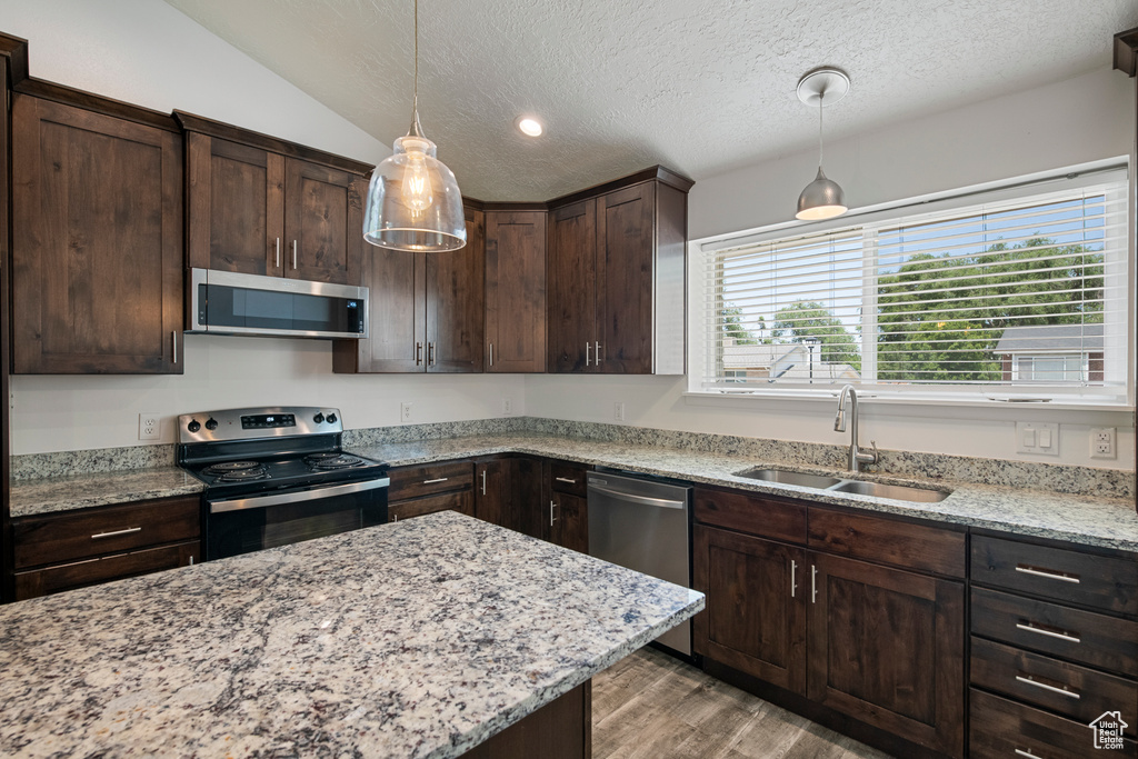Kitchen with stainless steel appliances, a sink, dark brown cabinets, a textured ceiling, and light wood finished floors