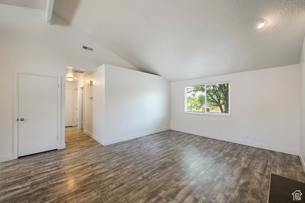 Unfurnished room featuring dark wood-type flooring, baseboards, and high vaulted ceiling