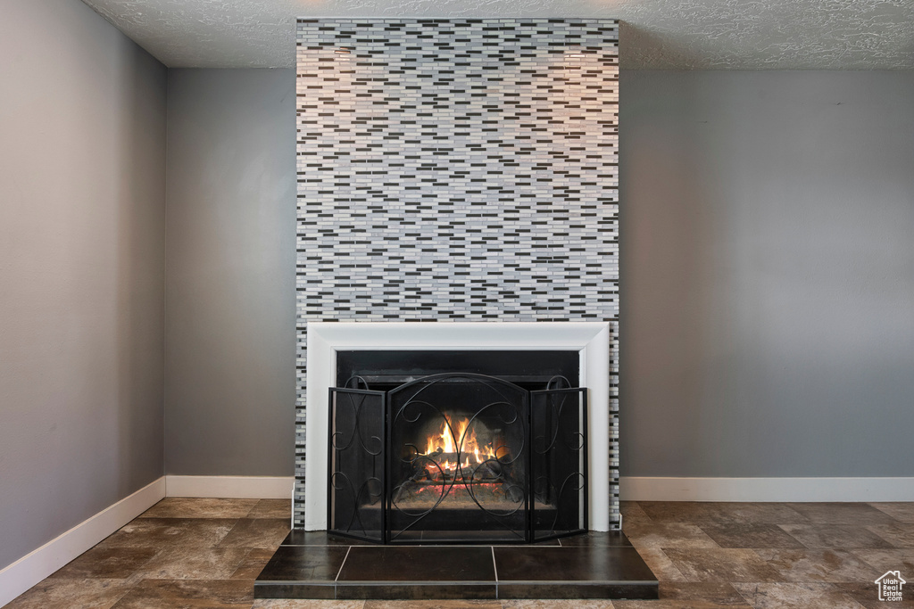 Detailed view of a textured ceiling, baseboards, and a fireplace