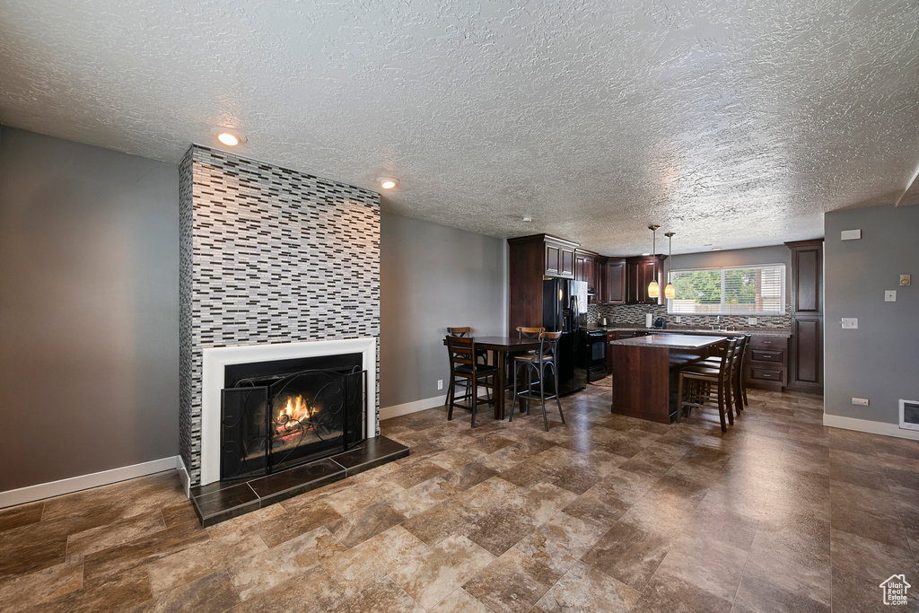 Living room featuring baseboards, a textured ceiling, a tiled fireplace, and recessed lighting