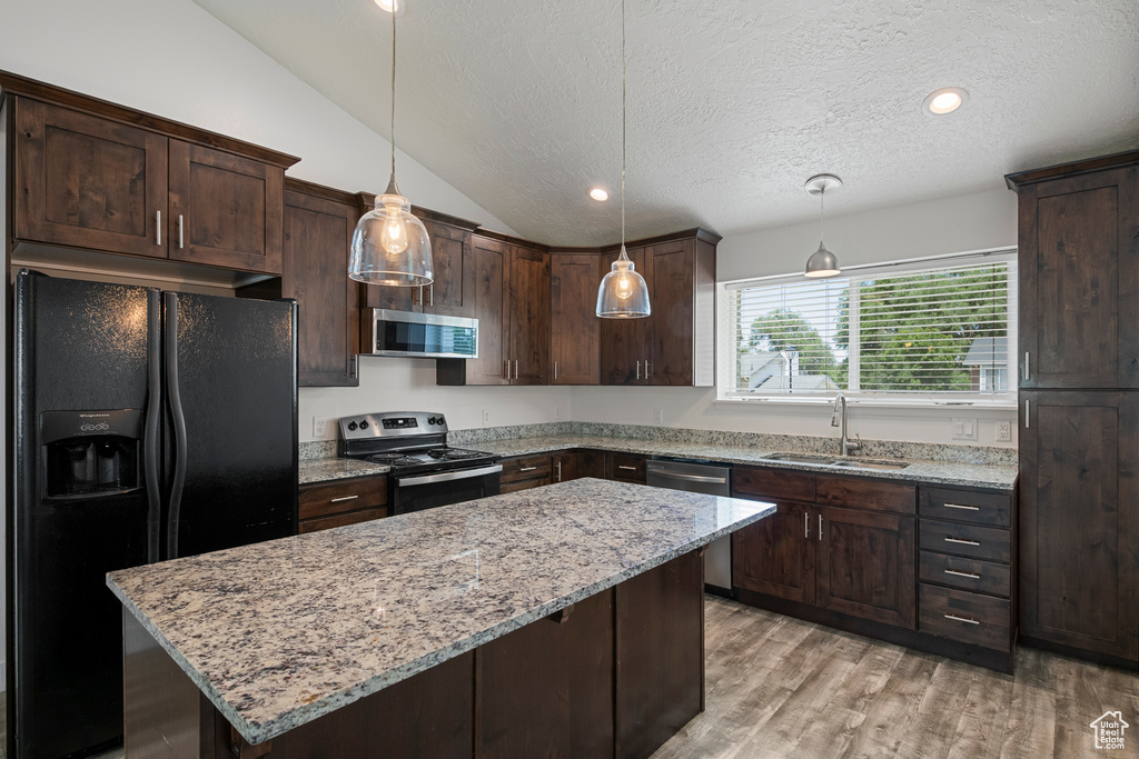 Kitchen featuring appliances with stainless steel finishes, a sink, dark brown cabinetry, lofted ceiling, and a textured ceiling