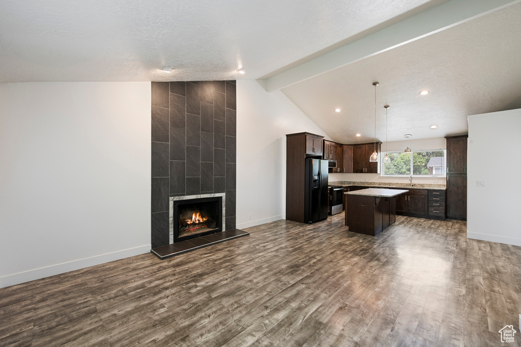 Unfurnished living room with dark wood finished floors, baseboards, a tile fireplace, recessed lighting, and a sink