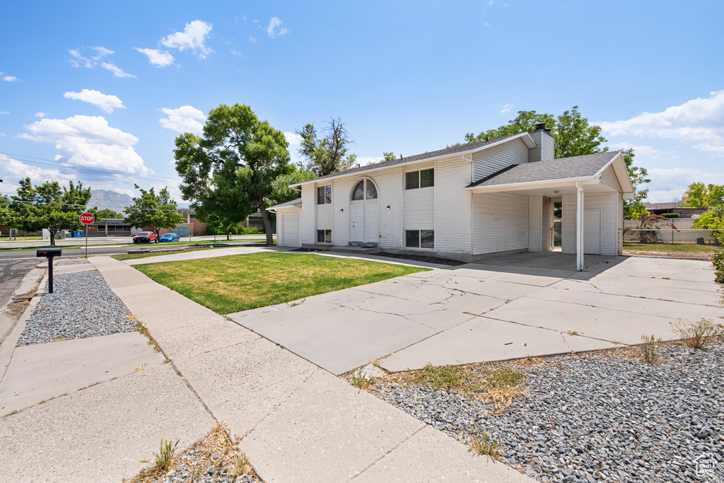 View of front of home with driveway, a chimney, a carport, brick siding, and a shingled roof