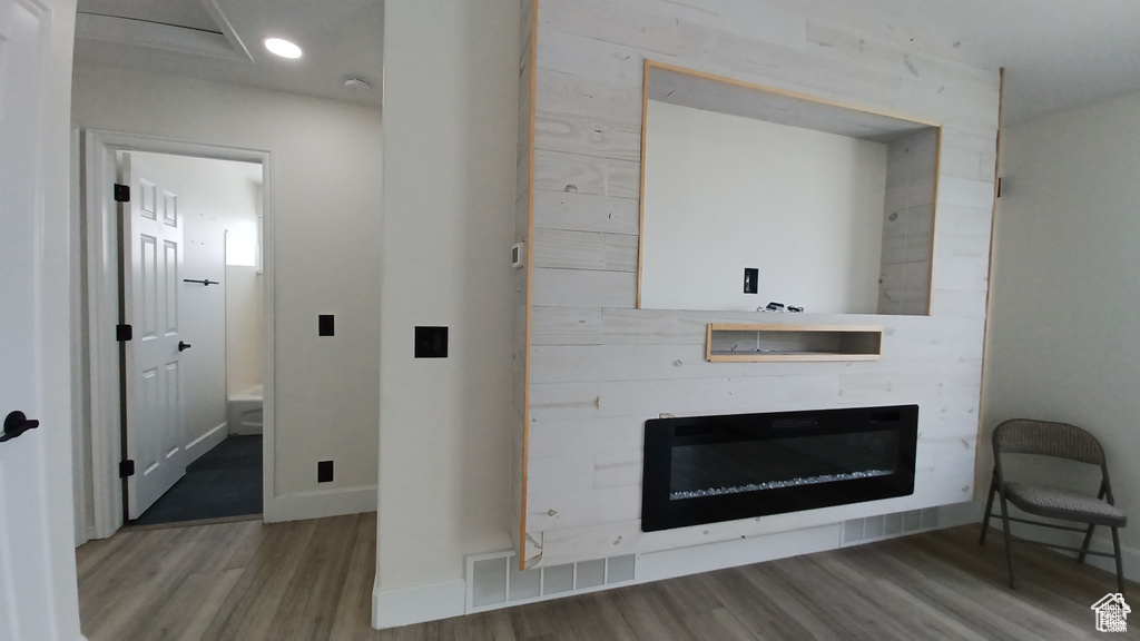 Unfurnished living room featuring wood finished floors, a glass covered fireplace, and recessed lighting