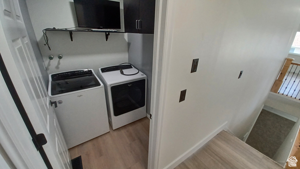 Washroom featuring independent washer and dryer and light wood-type flooring