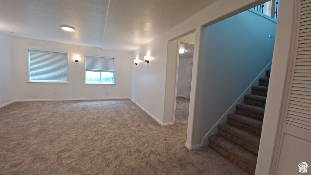 Carpeted spare room with stairway and baseboards