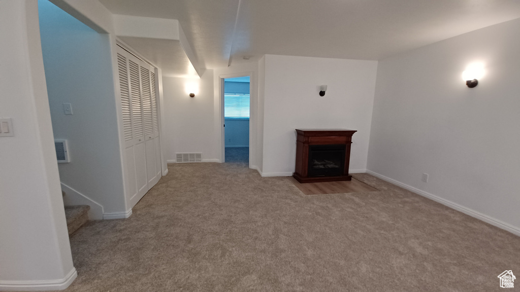 Unfurnished living room with carpet floors, a fireplace, and stairs