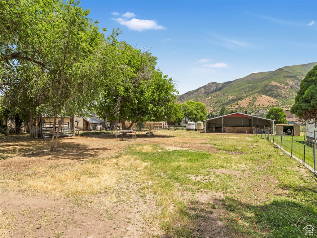 View of yard featuring a carport, a mountain view, an outbuilding, and an exterior structure