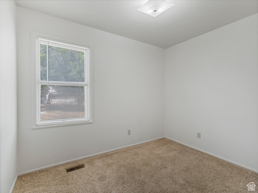 Spare room featuring carpet flooring and baseboards