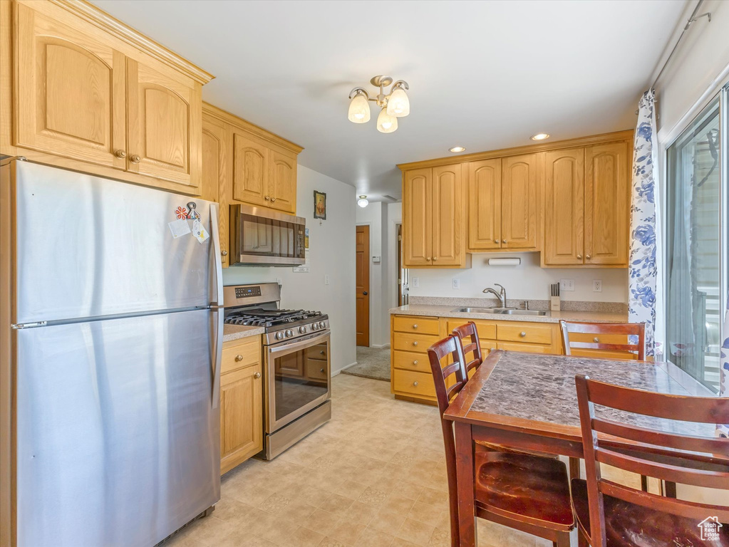 Kitchen with appliances with stainless steel finishes, light brown cabinetry, a sink, recessed lighting, and light countertops