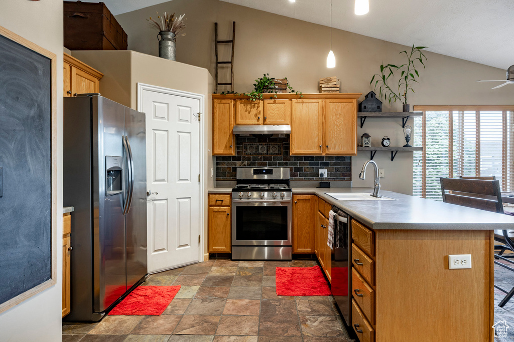 Kitchen featuring stainless steel appliances, lofted ceiling, decorative backsplash, under cabinet range hood, and stone finish flooring