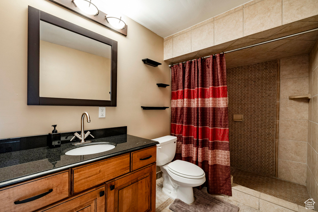 Full bath featuring a tile shower, vanity, and tile patterned flooring