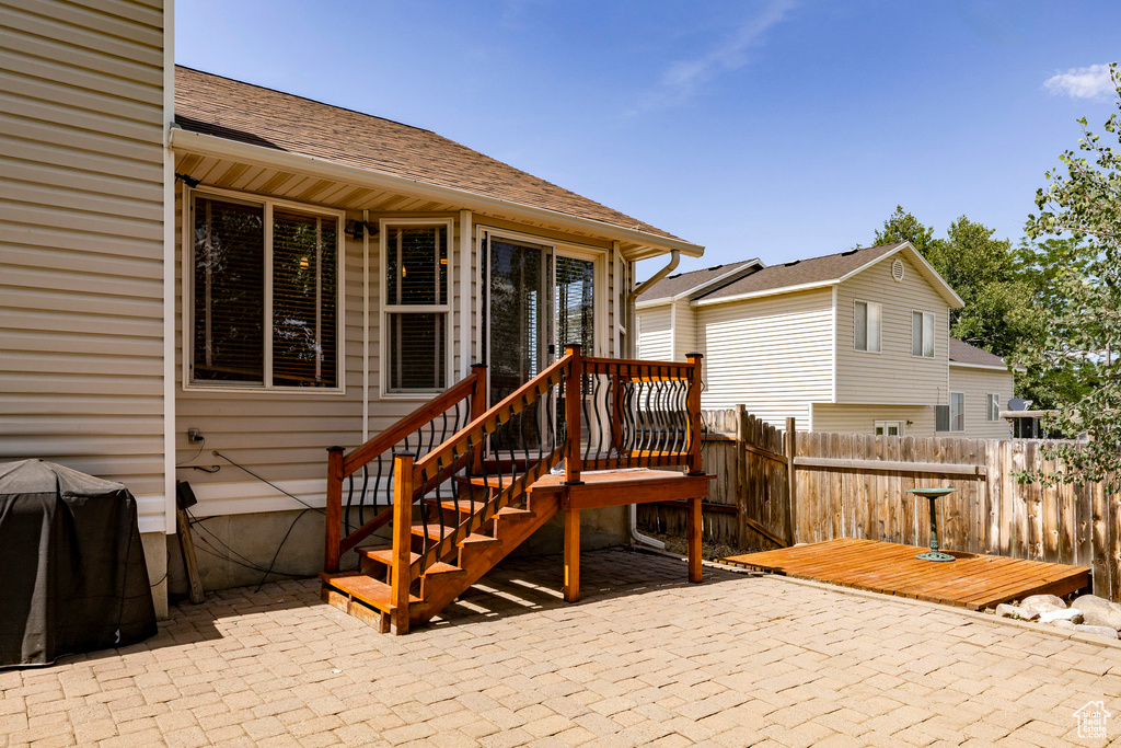 Back of house featuring a patio, a wooden deck, and a shingled roof