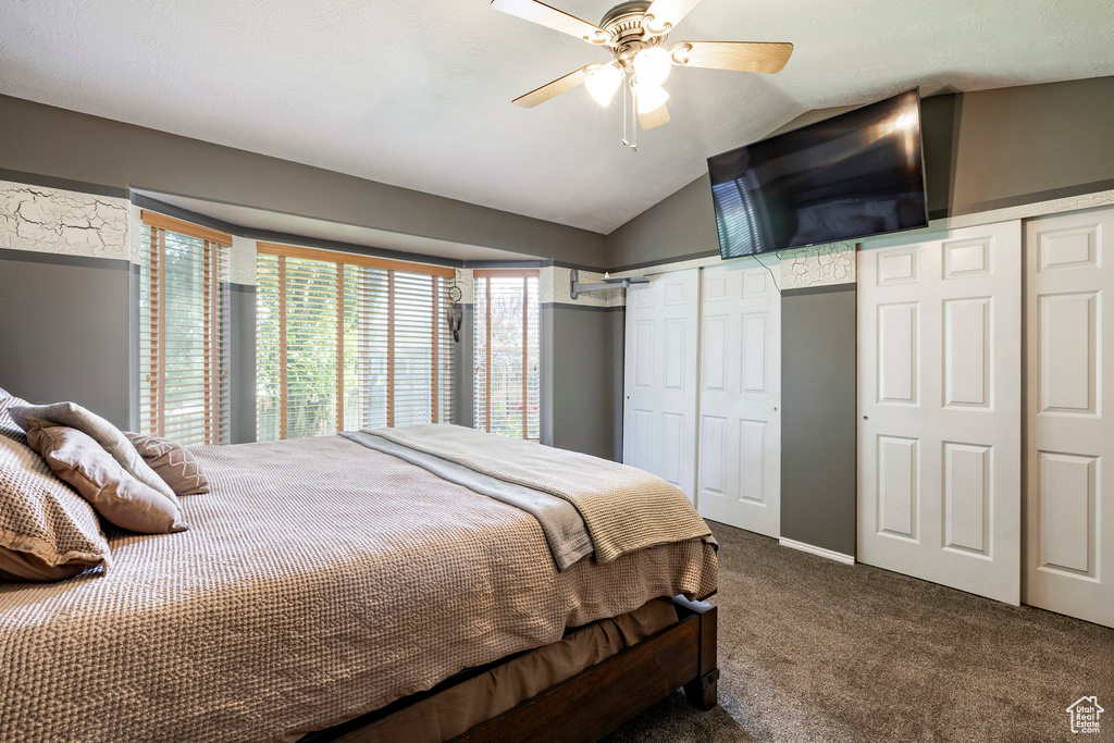 Bedroom with carpet floors, two closets, vaulted ceiling, and a ceiling fan