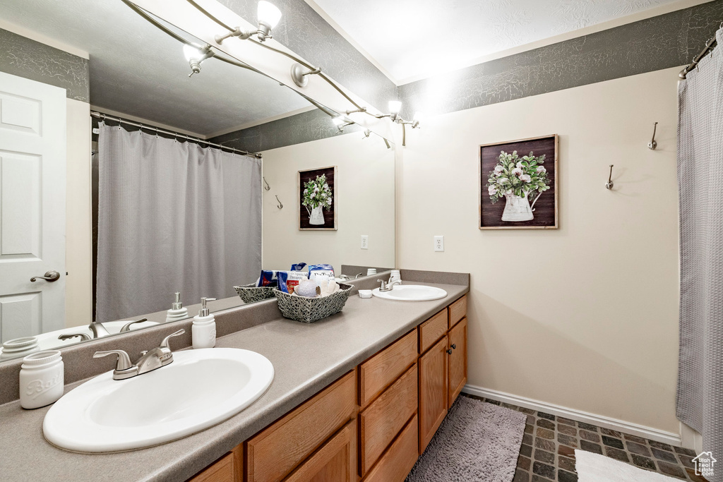 Full bathroom featuring double vanity, a shower with shower curtain, and stone finish flooring