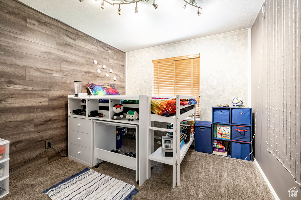 Carpeted bedroom featuring wood walls
