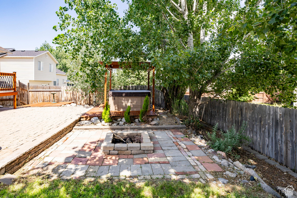 Fenced backyard with a fire pit, a patio area, and a hot tub