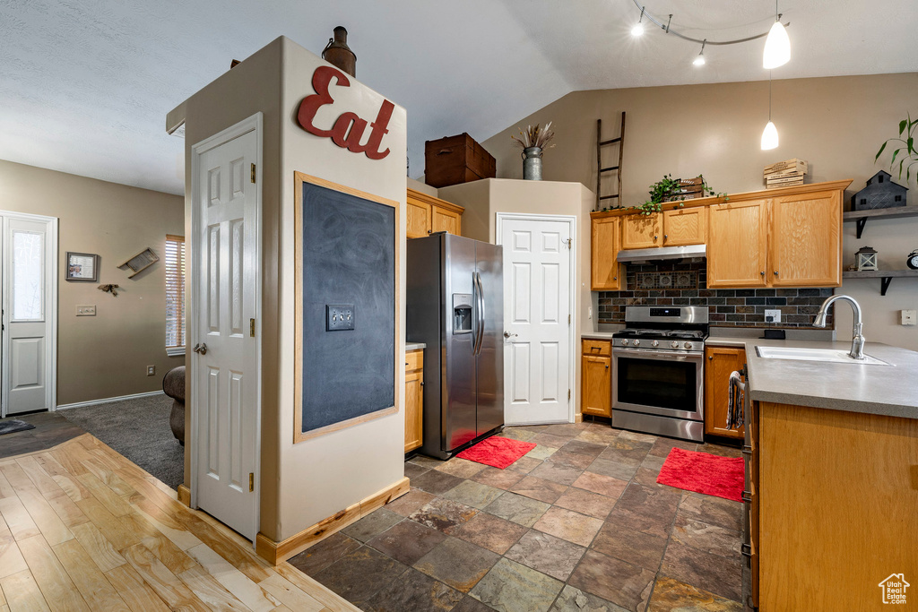 Kitchen featuring appliances with stainless steel finishes, under cabinet range hood, tasteful backsplash, open shelves, and vaulted ceiling