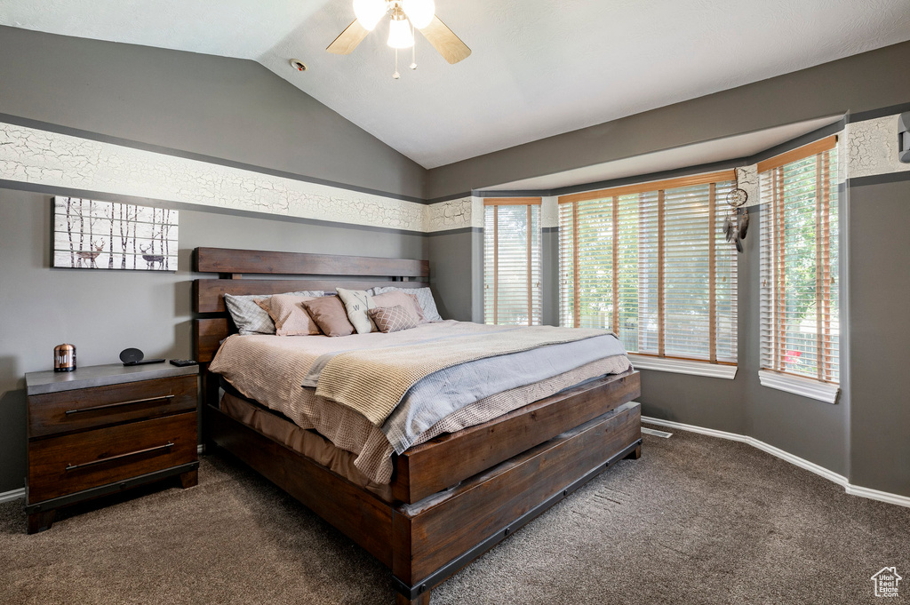 Bedroom with carpet flooring, lofted ceiling, multiple windows, and a ceiling fan