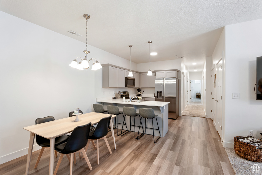 Kitchen with appliances with stainless steel finishes, a peninsula, light countertops, a kitchen breakfast bar, and a chandelier