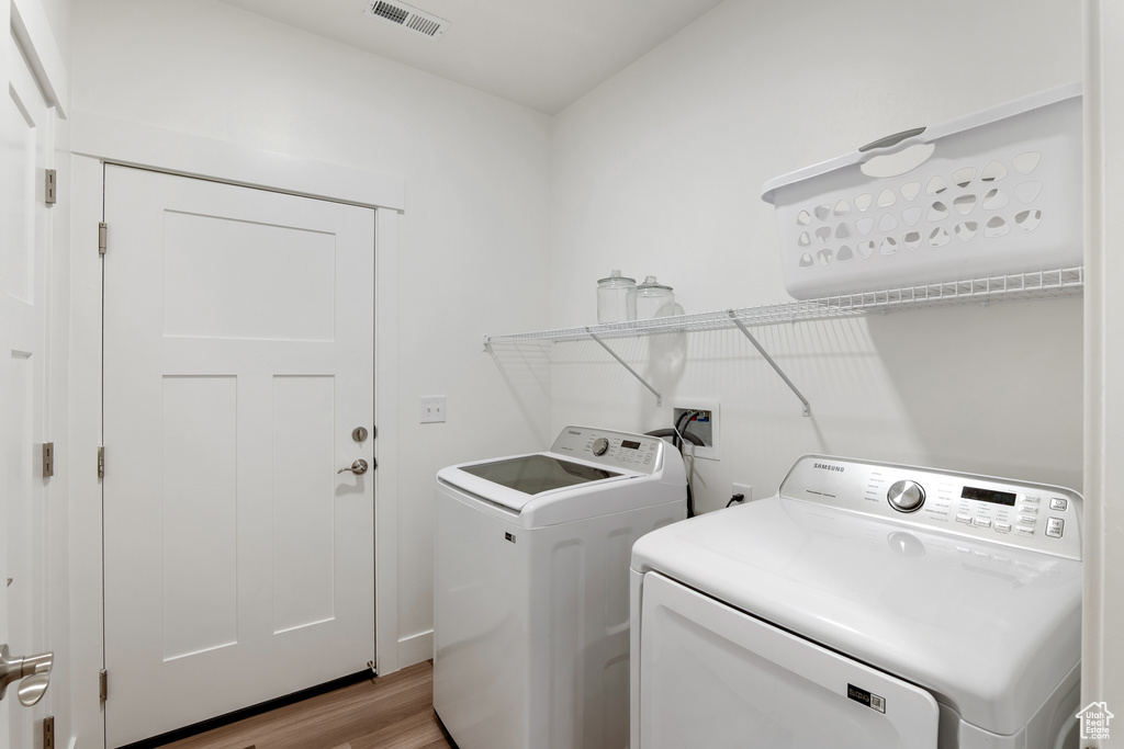 Laundry area with washing machine and clothes dryer and light wood finished floors