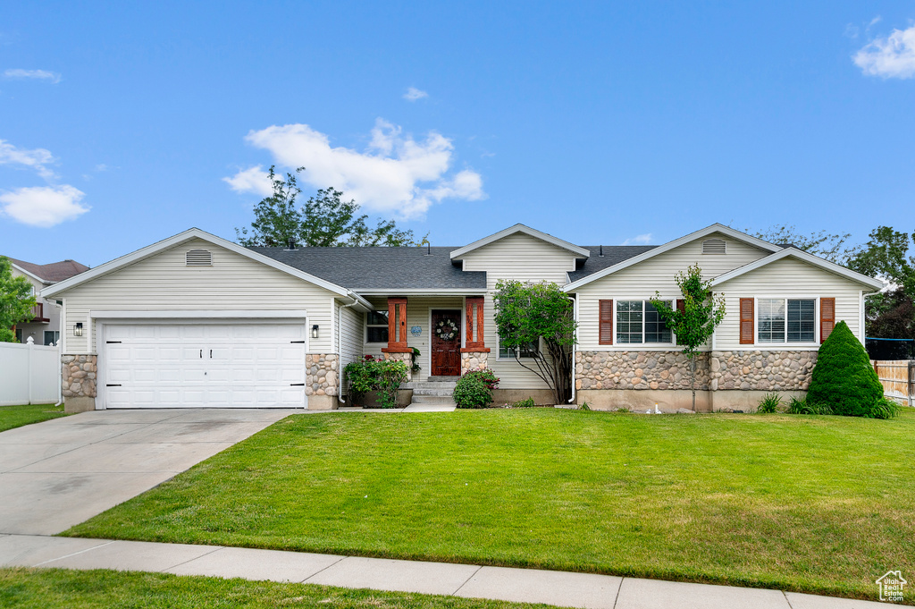 View of front of property with stone siding, a garage, concrete driveway, and roof with shingles