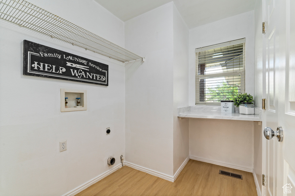 Laundry area with hookup for an electric dryer, washer hookup, and light wood-style floors