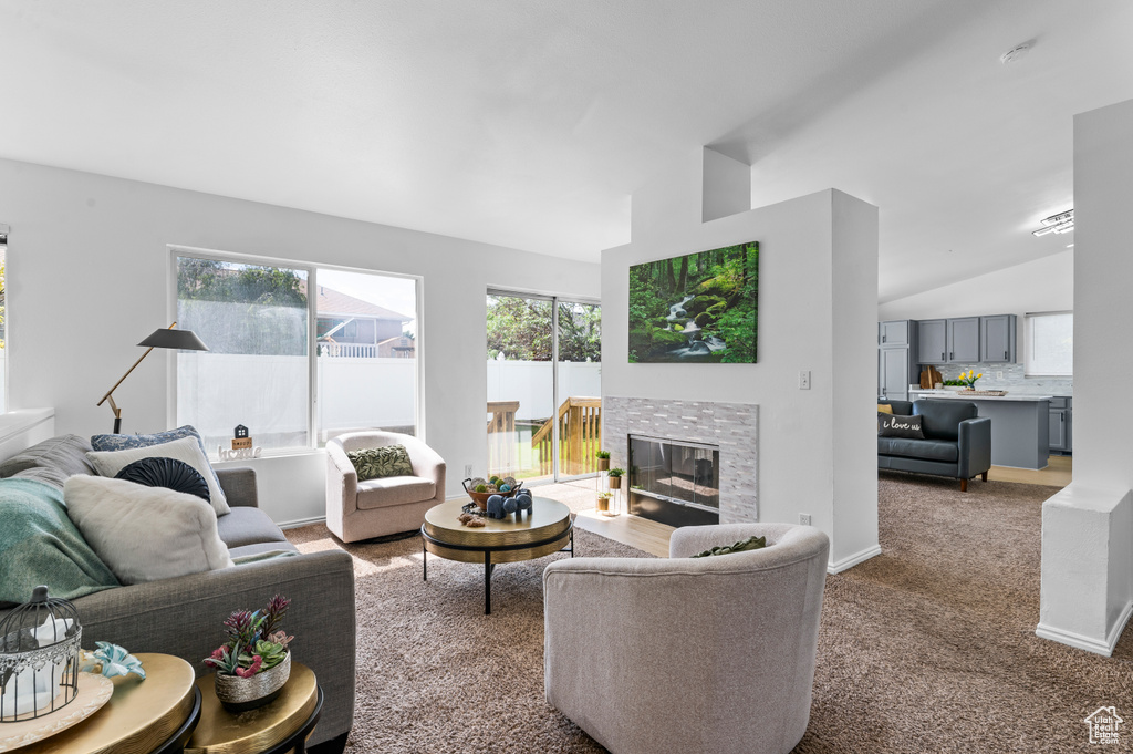 Living area with lofted ceiling, carpet floors, and a glass covered fireplace