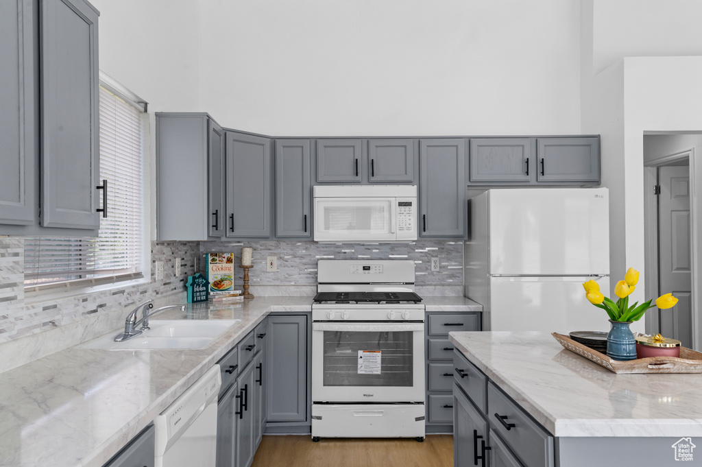 Kitchen featuring white appliances, gray cabinets, and decorative backsplash