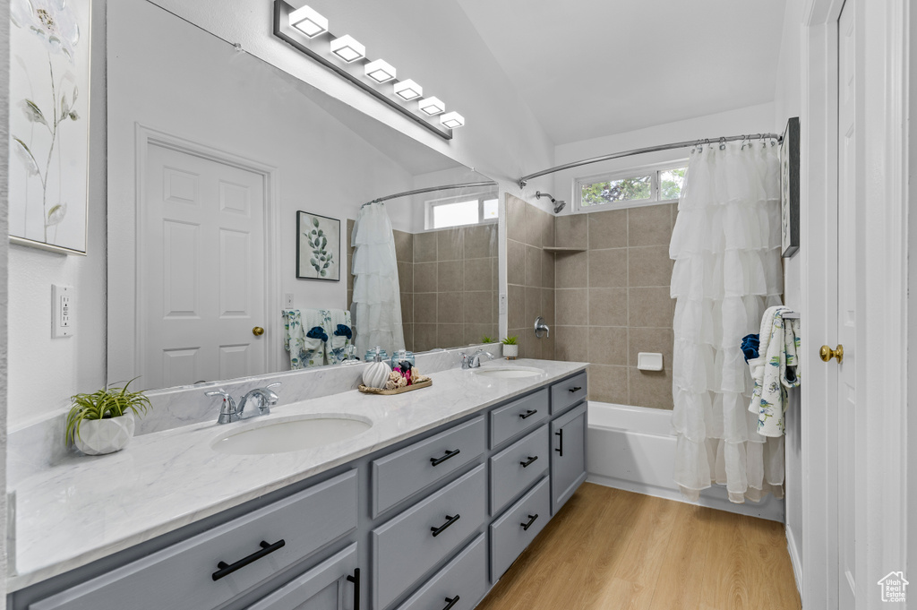 Full bath with shower / bath combination with curtain, double vanity, and wood finished floors