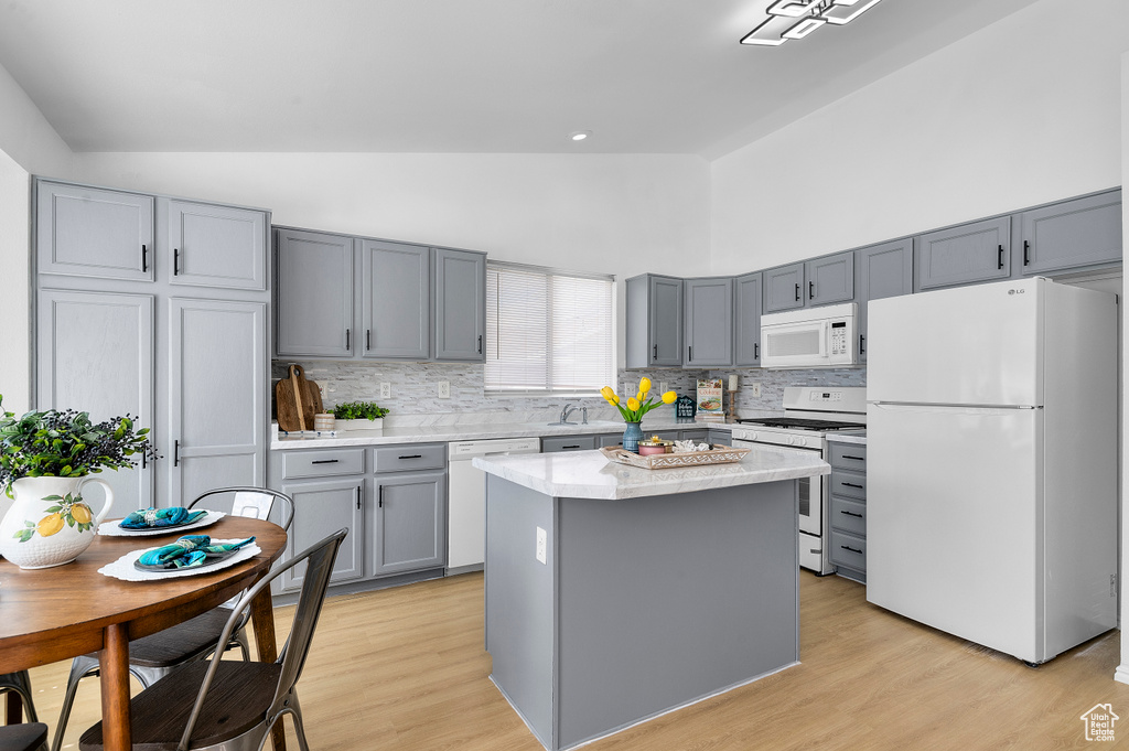 Kitchen featuring white appliances, gray cabinets, backsplash, high vaulted ceiling, and light wood-type flooring
