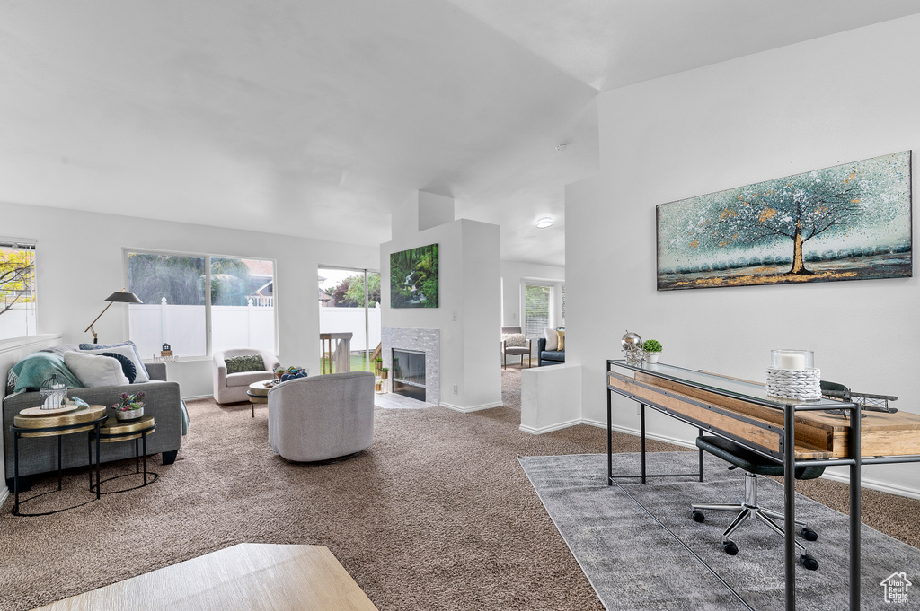 Carpeted living room with a tiled fireplace and lofted ceiling