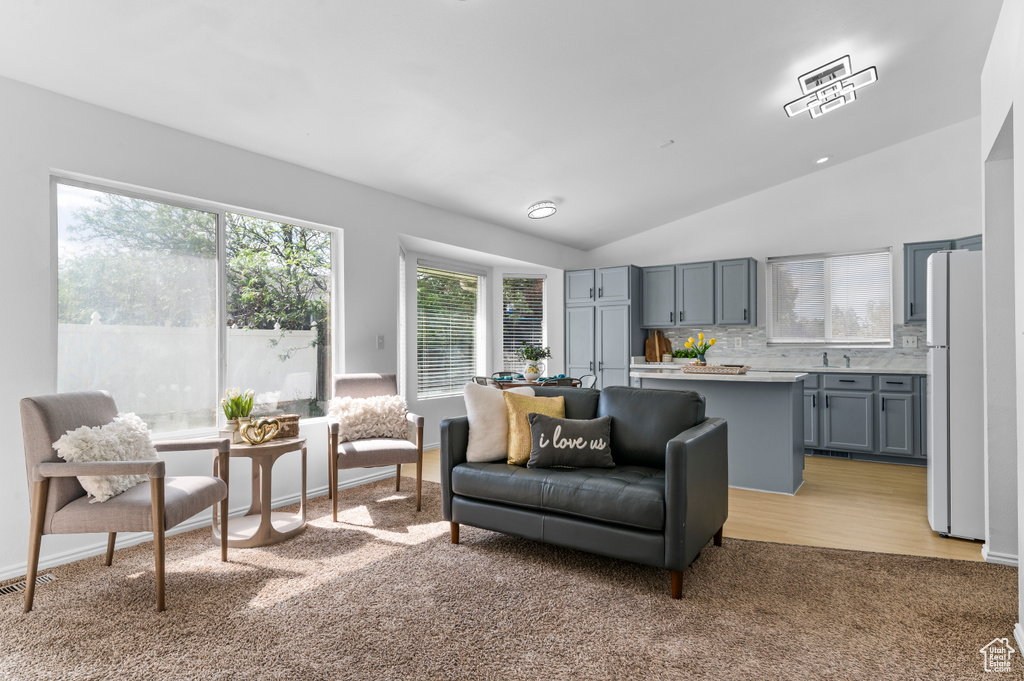 Living area with light carpet and lofted ceiling