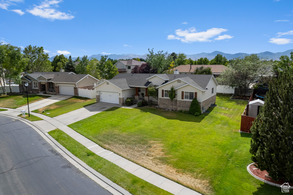 Ranch-style house with driveway, a residential view, a mountain view, and an attached garage