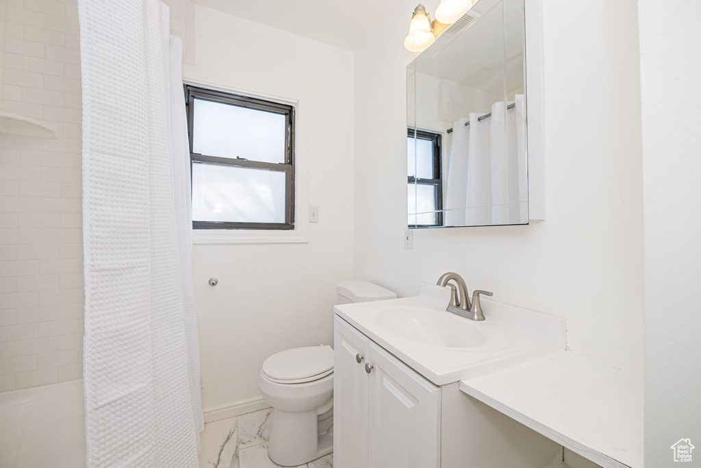 Full bath featuring vanity, marble finish floors, toilet, baseboards, and shower / bath combination with curtain