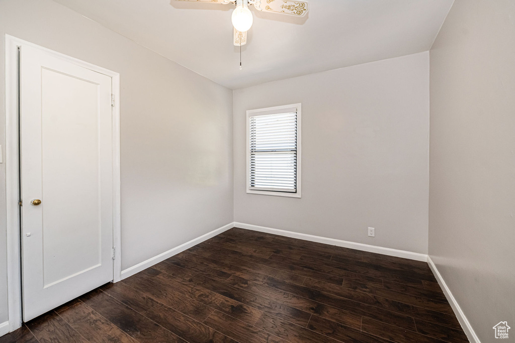 Unfurnished room with dark wood-style flooring, baseboards, and ceiling fan