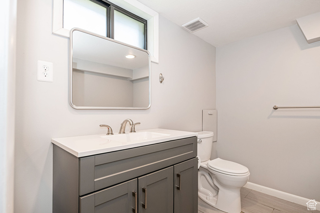Bathroom featuring toilet, vanity, and baseboards