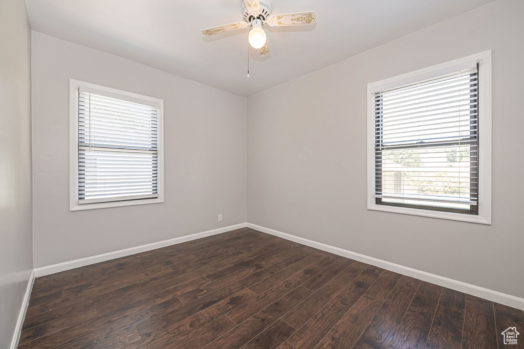 Spare room with baseboards, dark wood-style flooring, and a ceiling fan