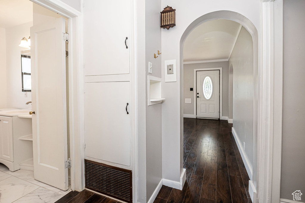 Foyer featuring arched walkways, crown molding, baseboards, and wood finished floors